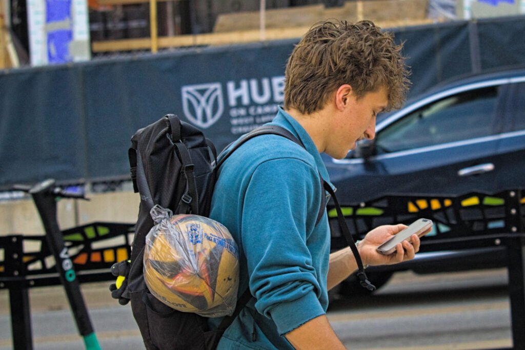 West Lafayette Downtown (Chauncey Village), 2026-03-29 - Man with Hair Looking at Cell Phone