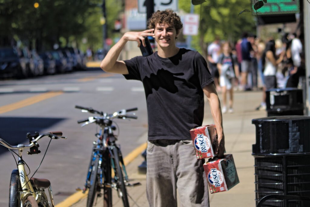 Man strolls the Village, walking proud holding his two packs of Busch Light Apple during Purdue's Grand Prix weekend