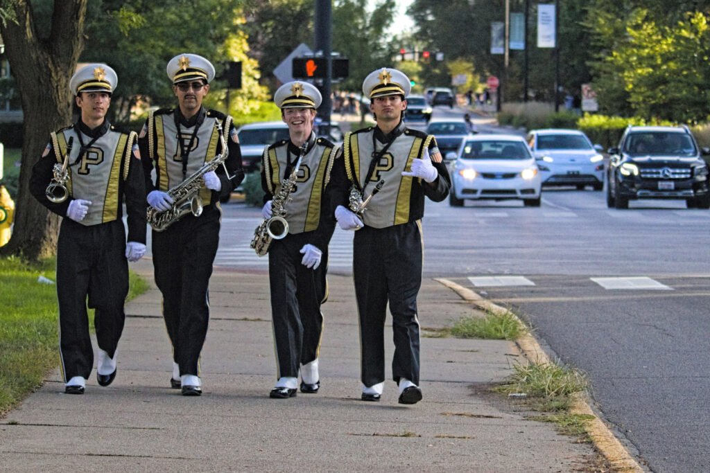 Four Purdue Marching Band saxophone players walk north on Grant Street